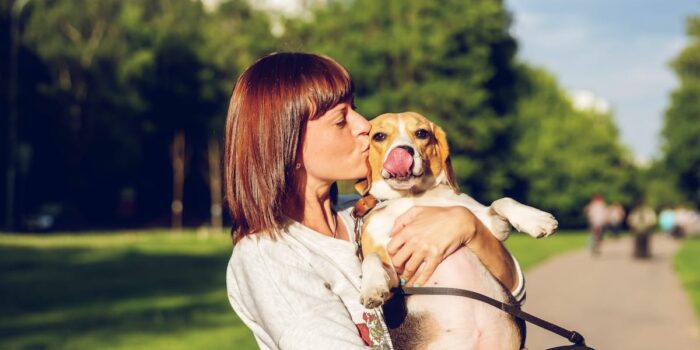 woman kissing dog at dog park