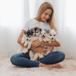latino woman holding pomsky puppies